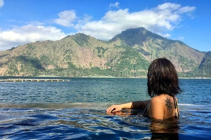 Woman relaxing in an infinity pool overlooking a lake and mountains